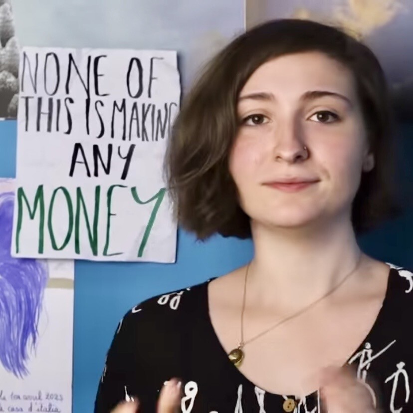 Lily Alexandre in front of a sign saying “None of this is making any money” 