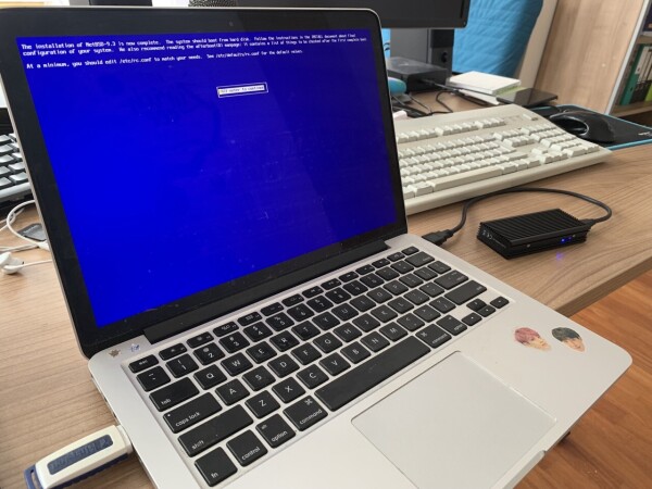 MacBook Pro on a desk, on the screen you can see the final success message from the NetBSD installer.