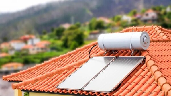 A solar water heater mounted on a tile roof with a scenic view of a hilly area in the background.