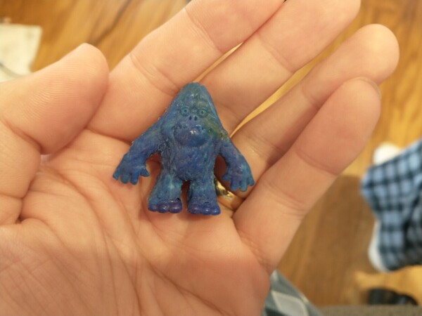 A small, mostly-blue molded-plastic sasquatch being held in an open hand.  He has a little bit of a derpy look on his face and definitely looks more friendly than abominable.